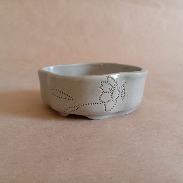 Piccolo vaso per mame bonsai in gres smaltato con un rametto di ciliegio inciso a piccoli puntini. Da un lato il ramo ha un fiore appena sbocciato, dall'altro due foglioline.