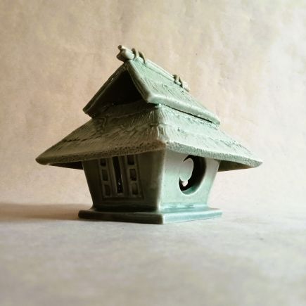 Brucia incensi a forma di capanna tradizionale giapponese. Di un verde tenero come un germoglio in primavera. Sul tetto corre una pianta di zucca.